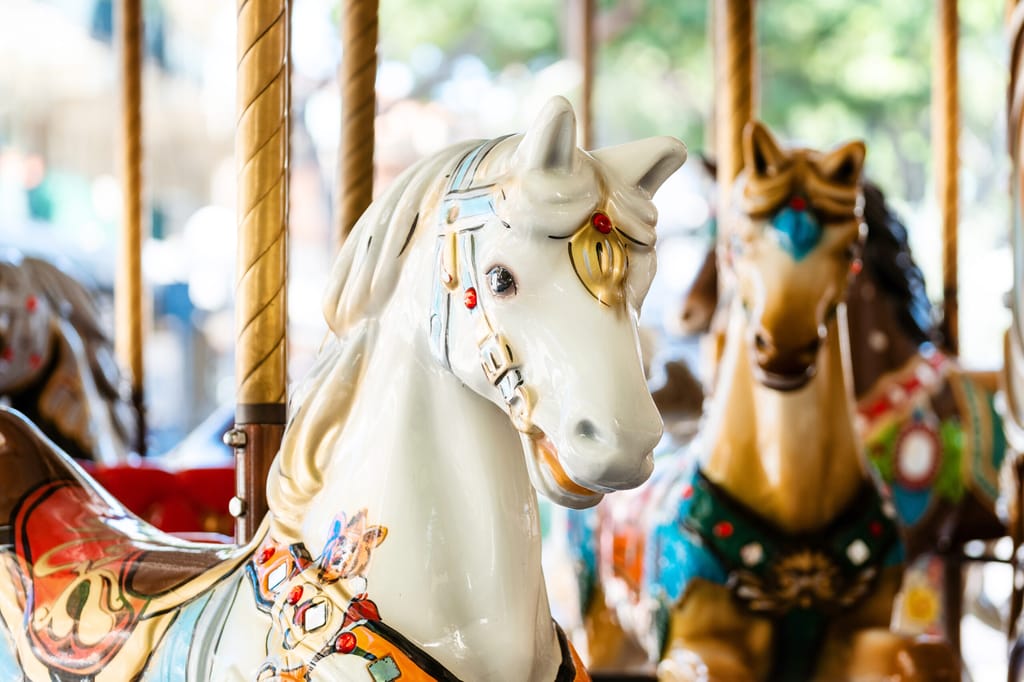 Vintage french carousel horse closeup in fair park. Merry-go-round horses in amusement fun park for children. Flying toy wooden animals in entertainment park